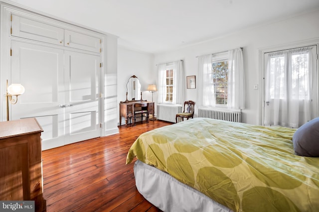 bedroom featuring wood-type flooring, access to outside, and radiator heating unit