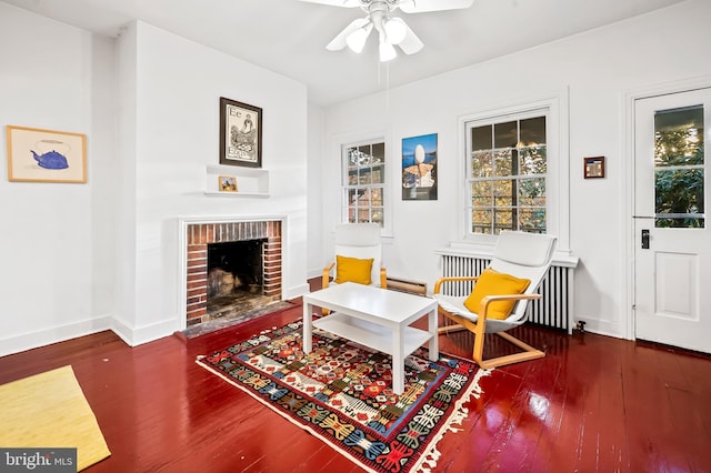 sitting room featuring ceiling fan, a baseboard heating unit, radiator heating unit, dark hardwood / wood-style floors, and a brick fireplace