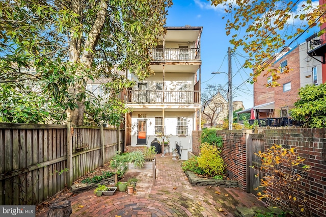 rear view of house featuring a patio and a balcony