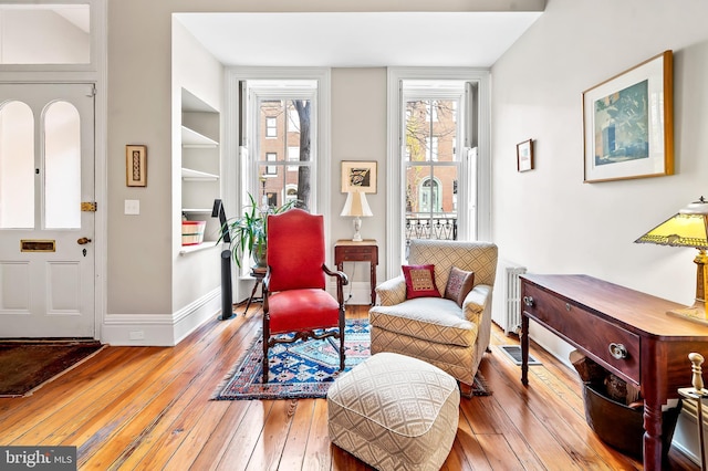 living area with built in shelves, radiator, and light hardwood / wood-style flooring