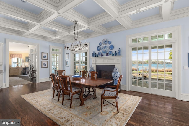 dining space with coffered ceiling, an inviting chandelier, a water view, and dark hardwood / wood-style flooring