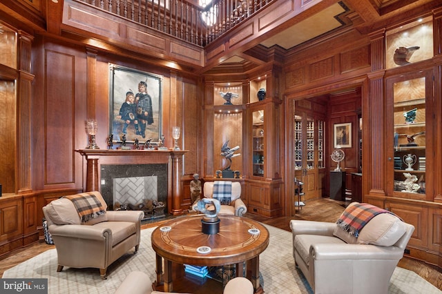 living room featuring coffered ceiling, wood walls, light hardwood / wood-style floors, and a towering ceiling