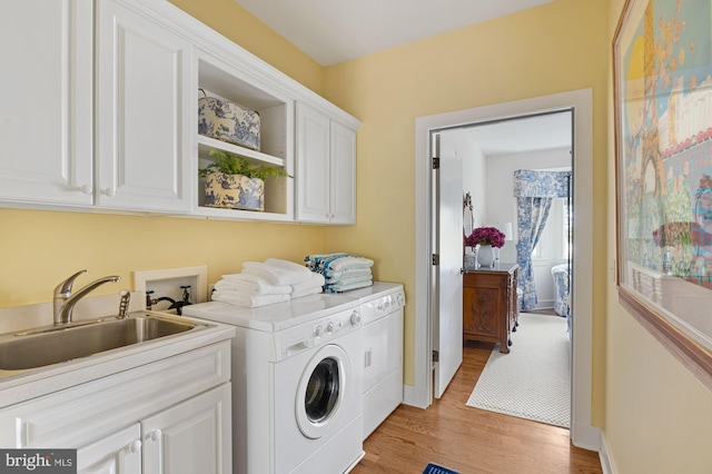 laundry room featuring cabinets, sink, light hardwood / wood-style flooring, washer hookup, and independent washer and dryer