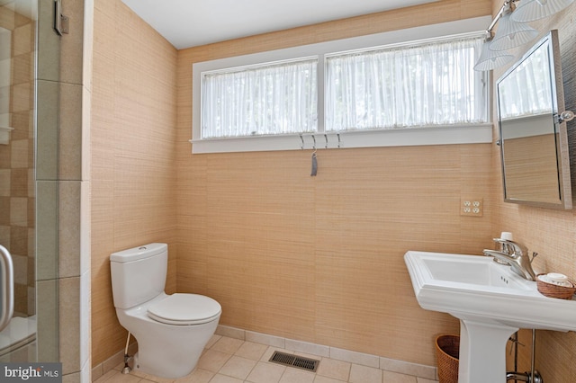 bathroom featuring tile walls, tile floors, toilet, and a healthy amount of sunlight