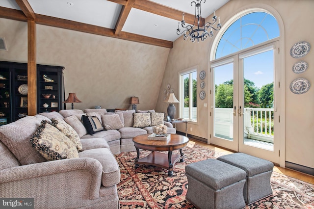 living room featuring an inviting chandelier, vaulted ceiling with beams, light hardwood / wood-style floors, and french doors