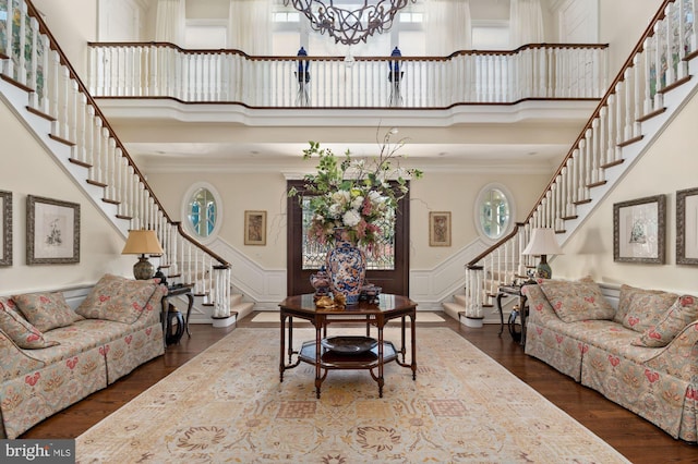 living room featuring crown molding, dark hardwood / wood-style floors, a notable chandelier, and a high ceiling