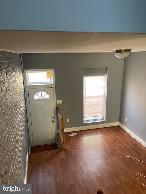 entrance foyer featuring brick wall and dark hardwood / wood-style flooring