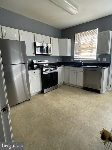 kitchen with light tile flooring, white cabinets, stainless steel appliances, and sink