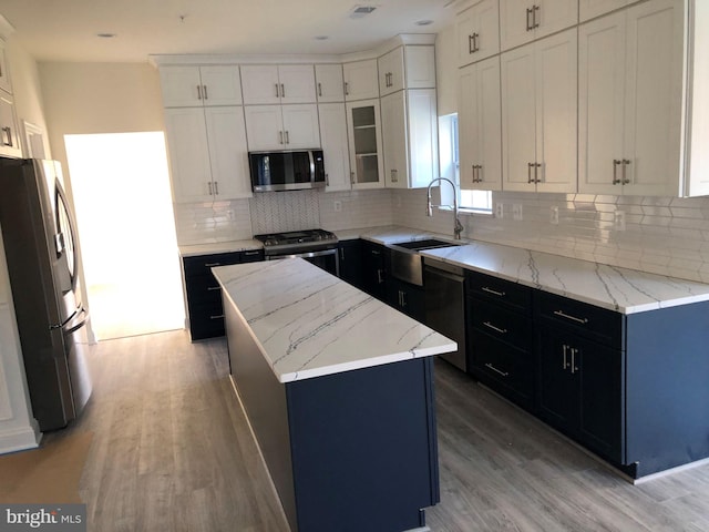 kitchen with appliances with stainless steel finishes, tasteful backsplash, white cabinetry, and light hardwood / wood-style floors