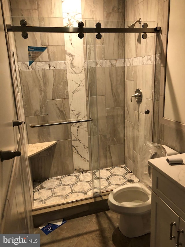 bathroom featuring vanity, a shower with door, tile flooring, and toilet