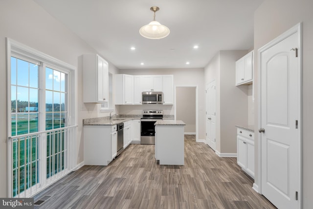 kitchen featuring white cabinetry, hanging light fixtures, stainless steel appliances, and a kitchen island