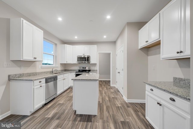 kitchen with stainless steel appliances, light stone countertops, and a center island