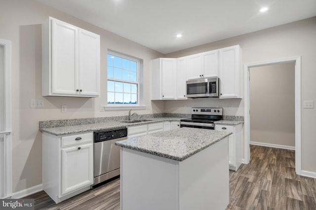 kitchen with light stone countertops, stainless steel appliances, white cabinets, and a kitchen island