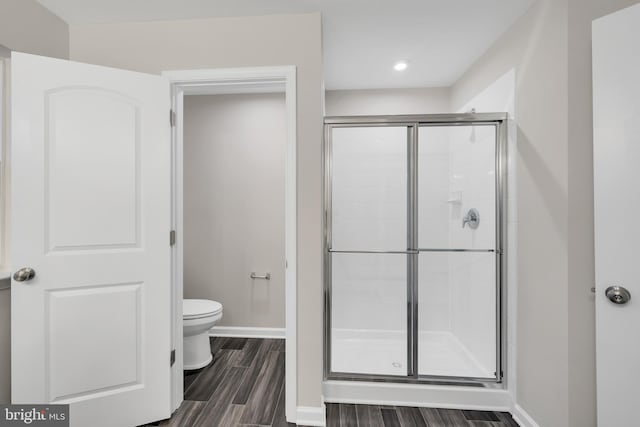 bathroom with toilet, hardwood / wood-style floors, and a shower with shower door