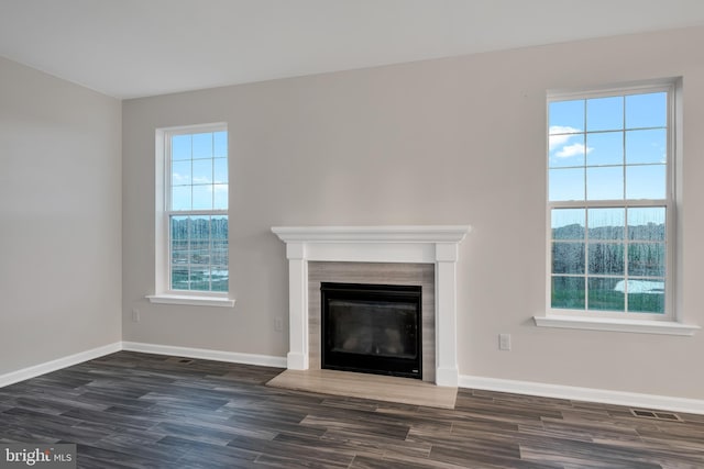 unfurnished living room featuring dark hardwood / wood-style flooring and a wealth of natural light