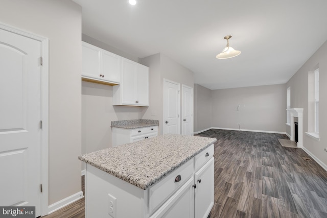 kitchen with a kitchen island, decorative light fixtures, white cabinetry, light stone countertops, and dark wood-type flooring