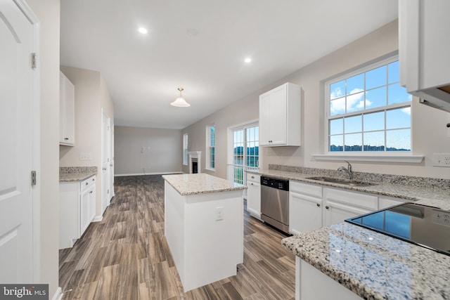 kitchen with sink, white cabinetry, a center island, stainless steel dishwasher, and light stone countertops