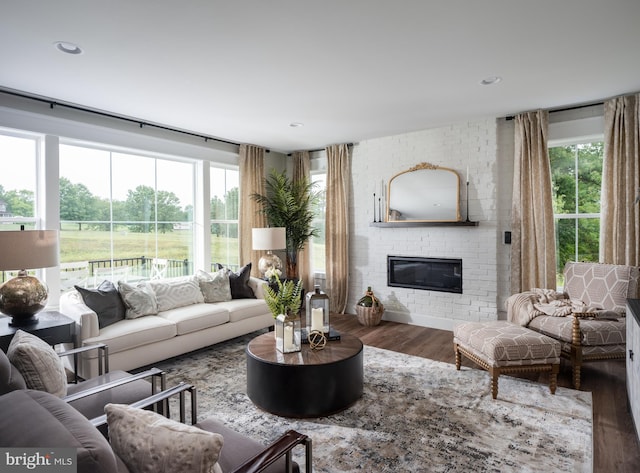 living room featuring a healthy amount of sunlight, a brick fireplace, and hardwood / wood-style flooring