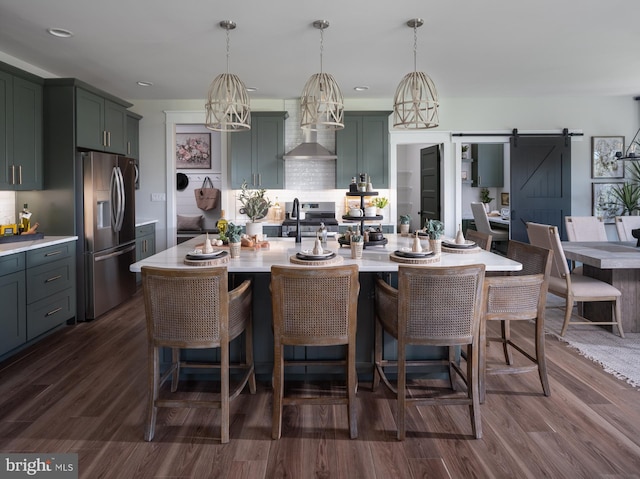 kitchen with hanging light fixtures, a barn door, dark hardwood / wood-style floors, and stainless steel appliances