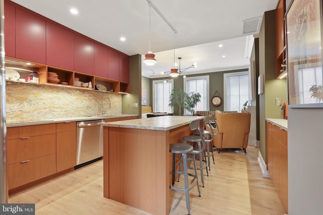 kitchen with a healthy amount of sunlight, a breakfast bar, light hardwood / wood-style flooring, a center island, and stainless steel dishwasher