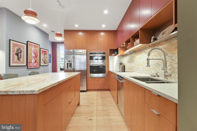 kitchen featuring pendant lighting, tasteful backsplash, stainless steel appliances, sink, and light hardwood / wood-style flooring