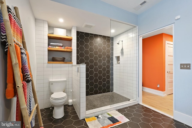 bathroom with tile walls, tile floors, toilet, and a tile shower