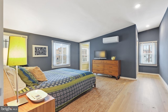 bedroom featuring lofted ceiling, a wall mounted air conditioner, and light hardwood / wood-style flooring