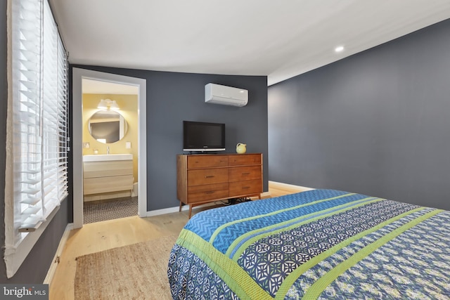 bedroom featuring connected bathroom, light hardwood / wood-style floors, lofted ceiling, multiple windows, and a wall unit AC