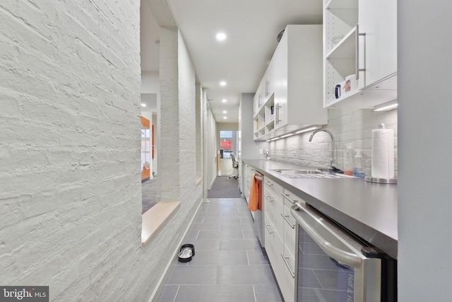 kitchen featuring stainless steel dishwasher, white cabinets, dark tile floors, dishwasher, and sink