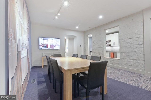 carpeted dining space featuring rail lighting