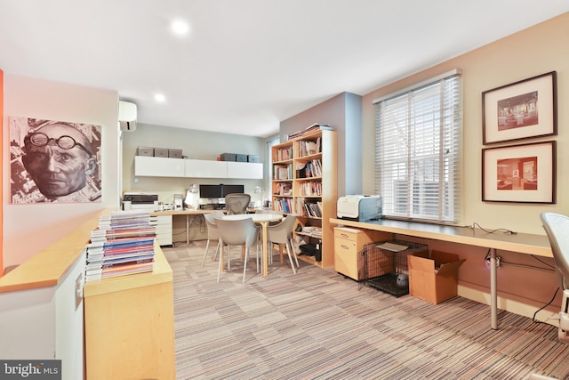 home office with built in desk, a wall mounted AC, and light colored carpet