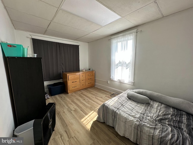 bedroom with light hardwood / wood-style flooring and a paneled ceiling