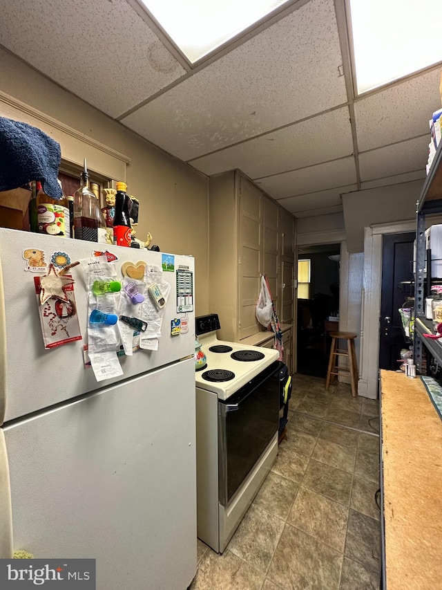 kitchen featuring tile flooring, white appliances, and a paneled ceiling