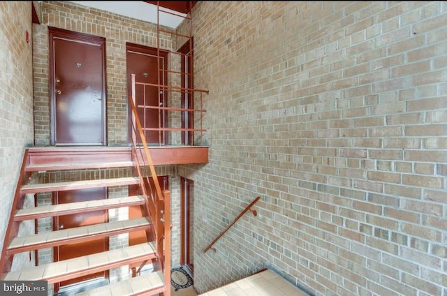 staircase featuring brick wall