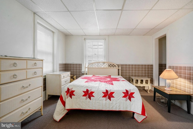 carpeted bedroom featuring a drop ceiling