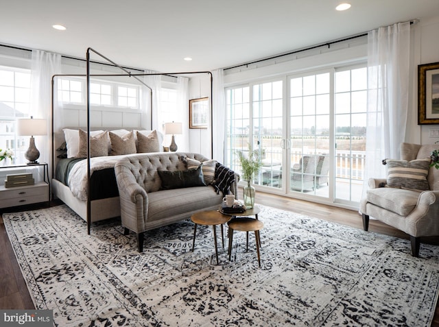 bedroom with hardwood / wood-style floors, multiple windows, and access to outside