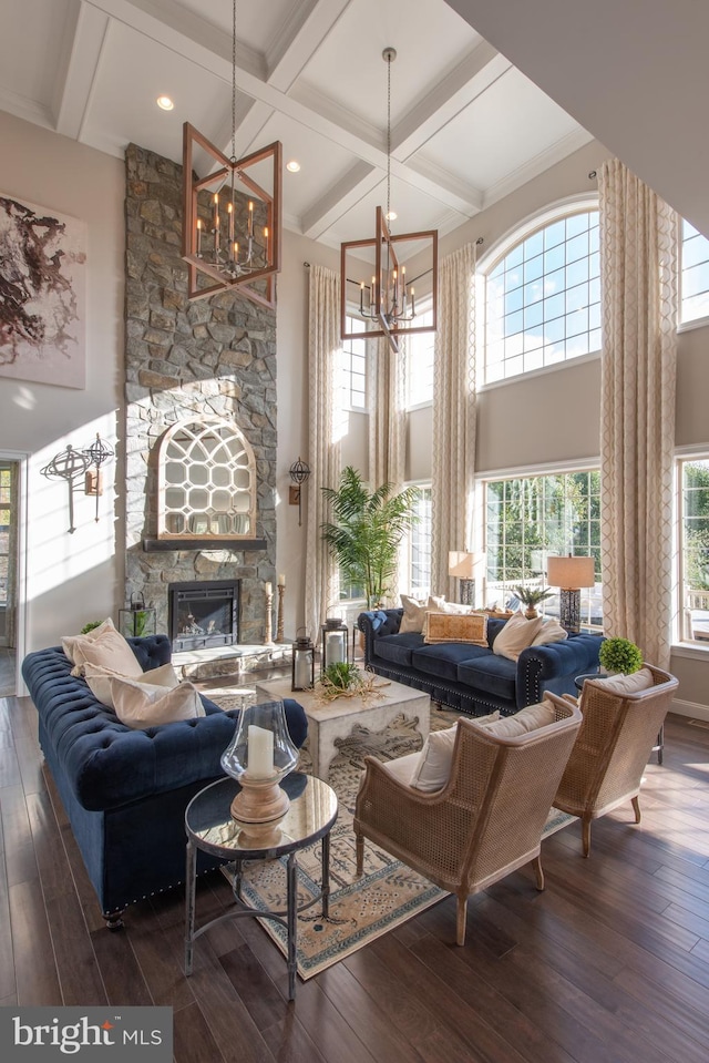 living room with coffered ceiling, a stone fireplace, dark wood-type flooring, and an inviting chandelier