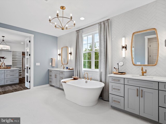 bathroom featuring tile patterned flooring, vanity, a bath, tasteful backsplash, and a chandelier