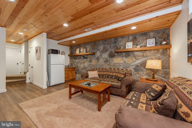 living room featuring beam ceiling, wood ceiling, a fireplace, and light wood-type flooring