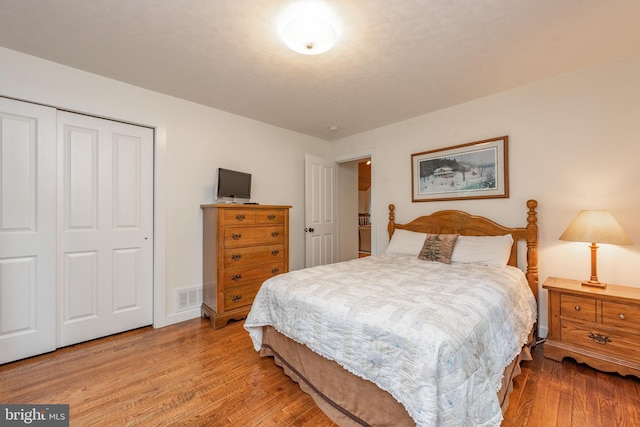 bedroom with light hardwood / wood-style floors and a closet