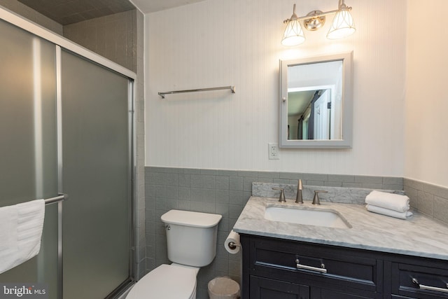 bathroom featuring an enclosed shower, vanity, toilet, and tile walls