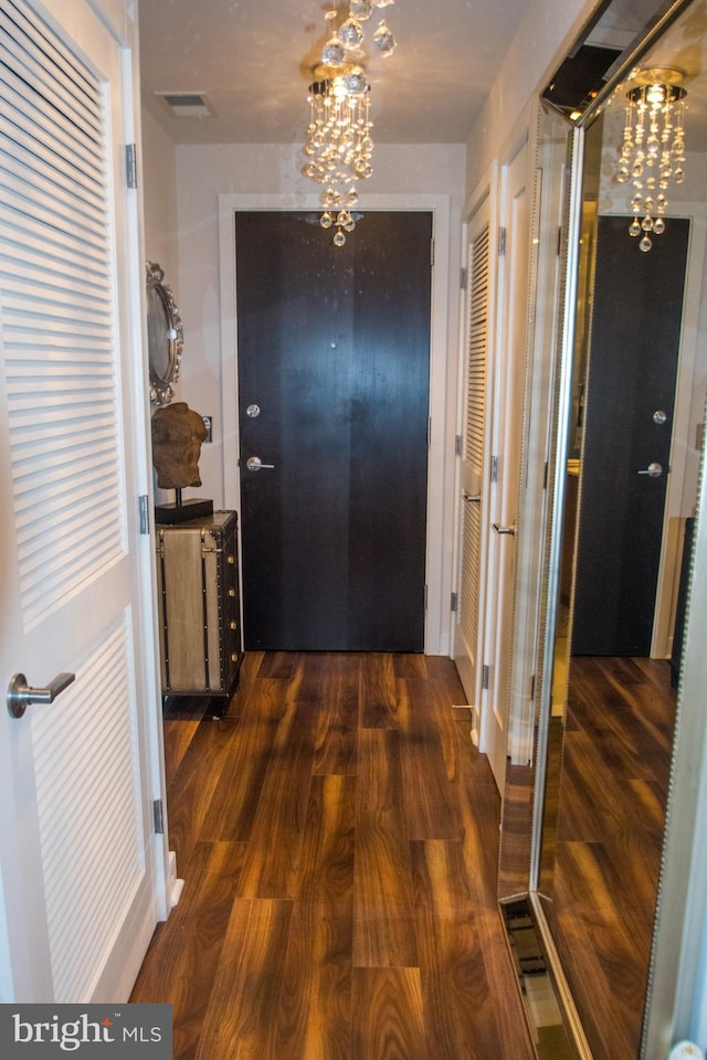 hallway featuring an inviting chandelier and dark wood-type flooring