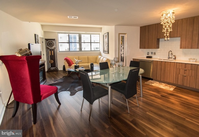 dining area featuring a notable chandelier, sink, and dark hardwood / wood-style flooring