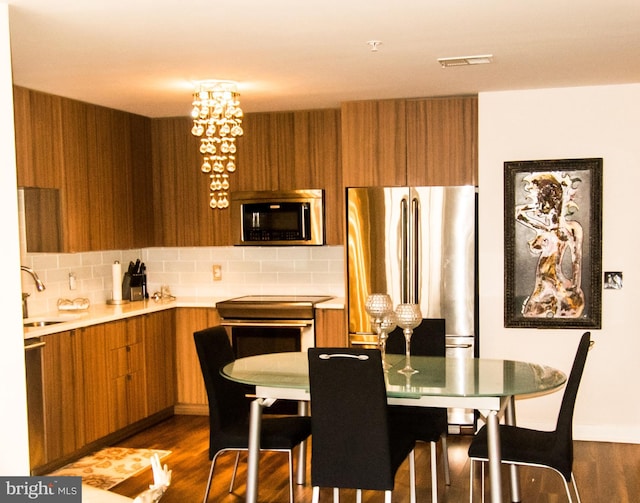 dining space with dark hardwood / wood-style flooring, sink, and a notable chandelier