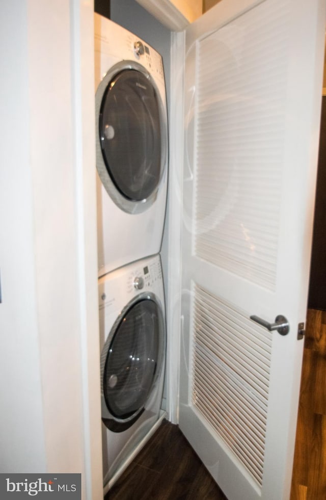 washroom featuring stacked washing maching and dryer and dark hardwood / wood-style flooring