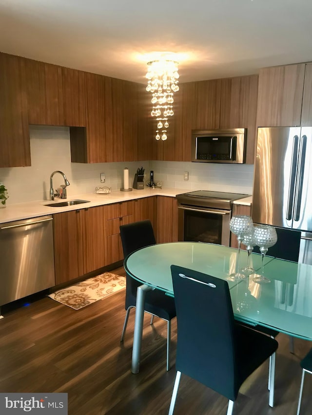 kitchen featuring a notable chandelier, sink, stainless steel appliances, tasteful backsplash, and dark hardwood / wood-style flooring