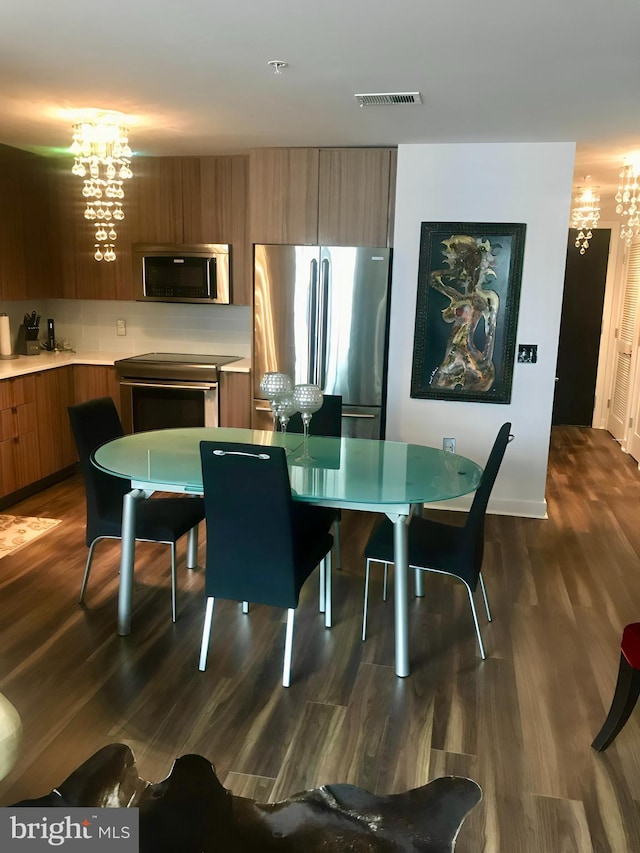 kitchen featuring an inviting chandelier, stainless steel appliances, and dark wood-type flooring