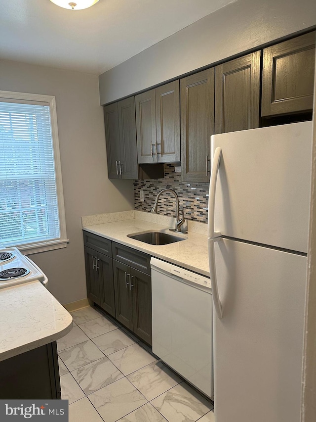 kitchen featuring tasteful backsplash, white appliances, light tile floors, sink, and dark brown cabinets