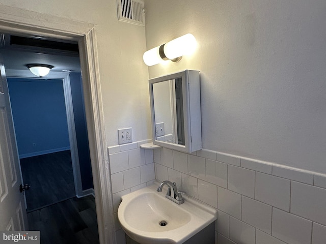 bathroom with tile walls, sink, tasteful backsplash, and wood-type flooring