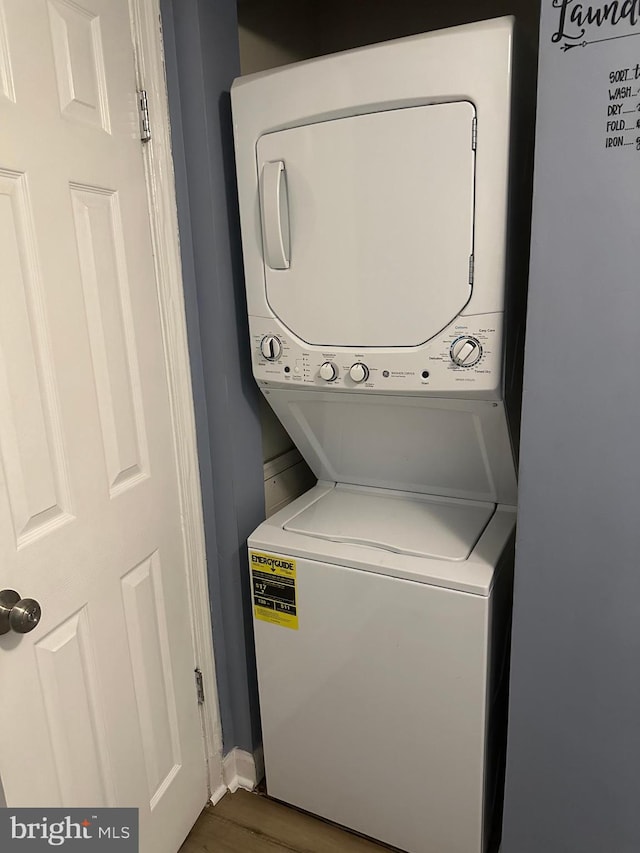 laundry area with stacked washer and dryer and dark wood-type flooring